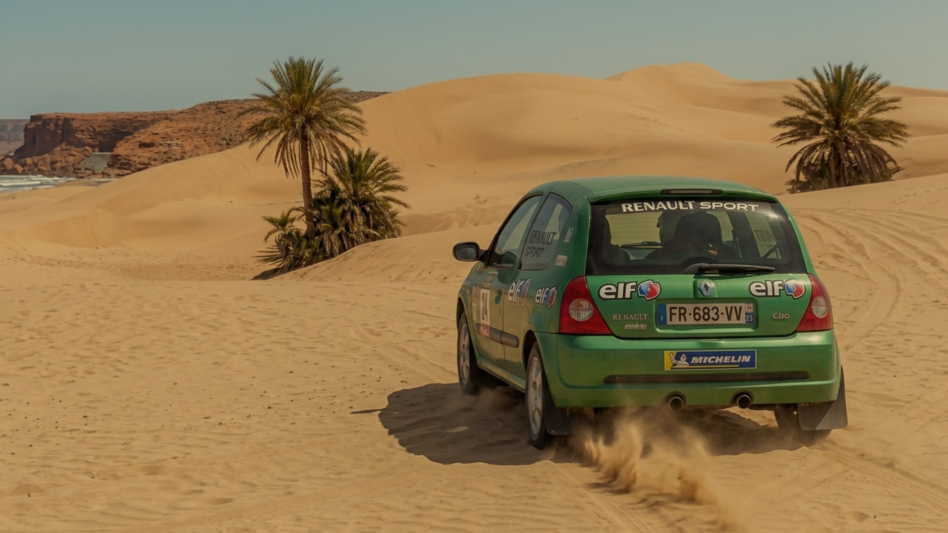 Clio verte dans les dunes avec des palmiers
